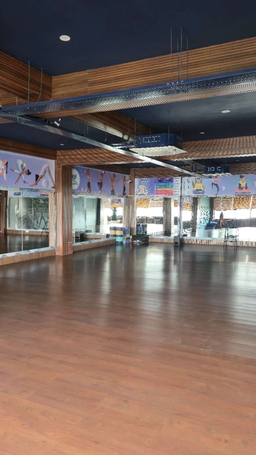 Portrait view of the yoga and group-class room with wooden floor, mirrors and stacked mats and equipment
