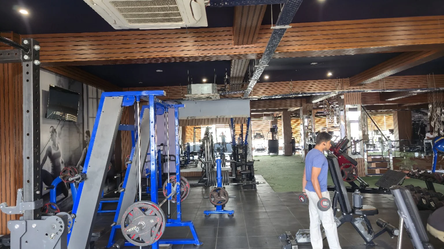 Diagonal view of blue strength equipment with a member exercising with dumbbells
