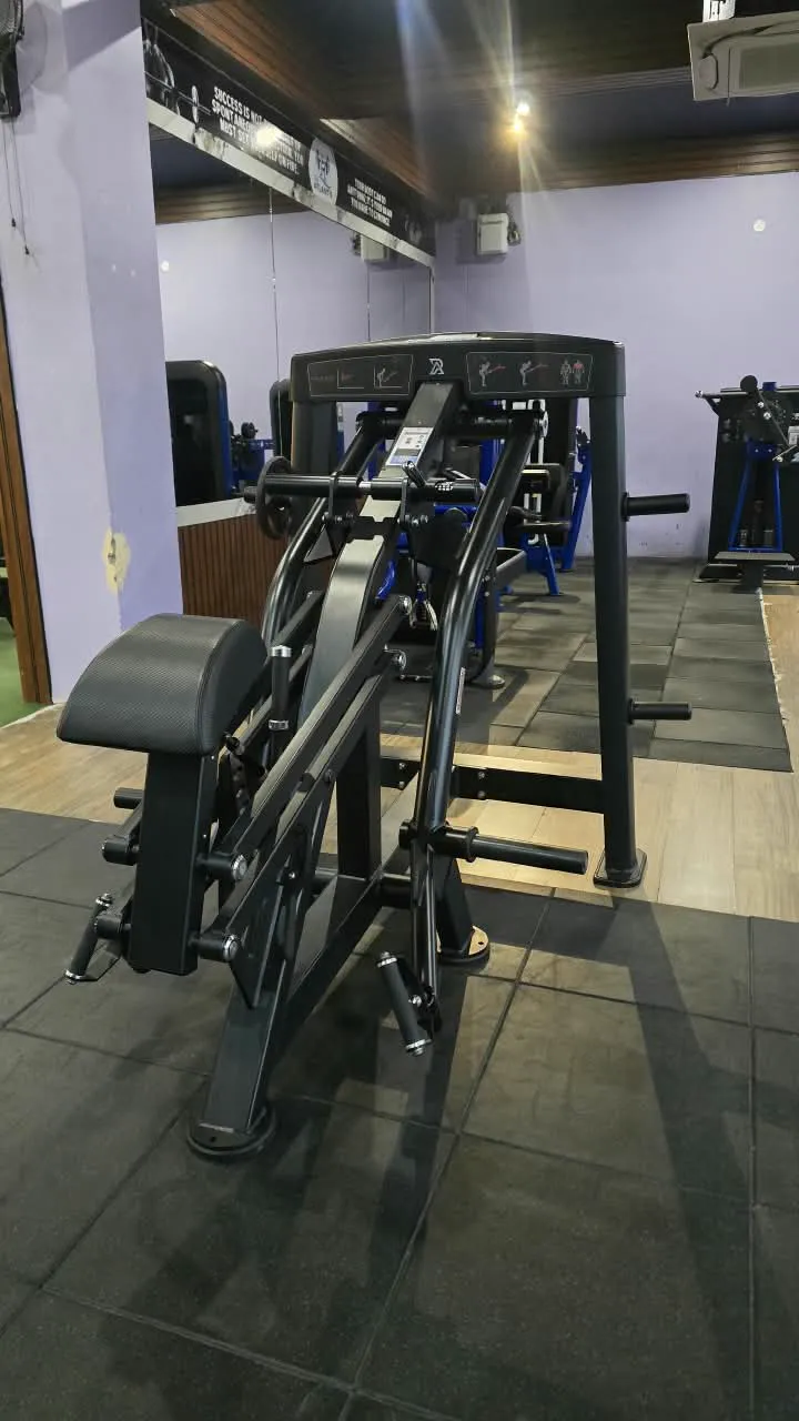 Black plate-loaded row machine with a chest pad on the gym floor
