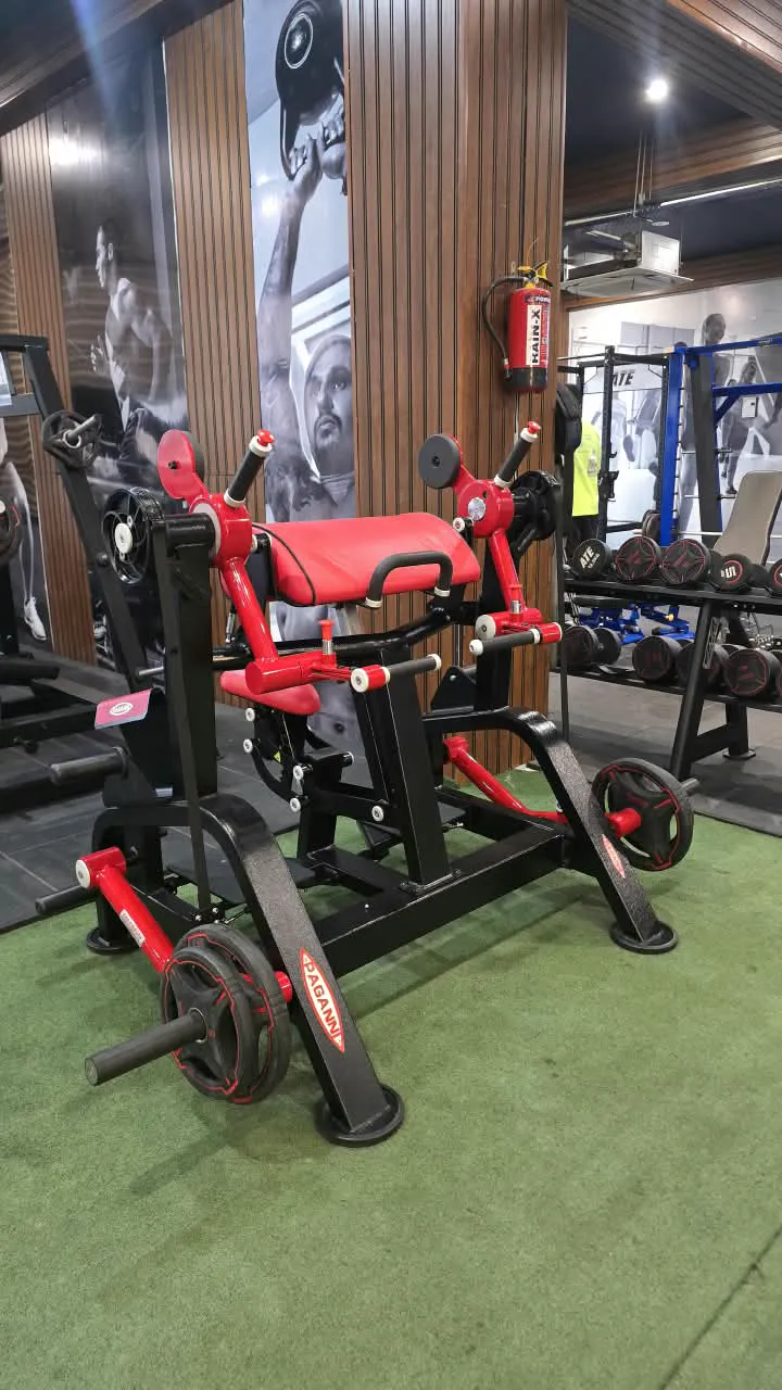 Red and black glute training machine with weight plates on green turf