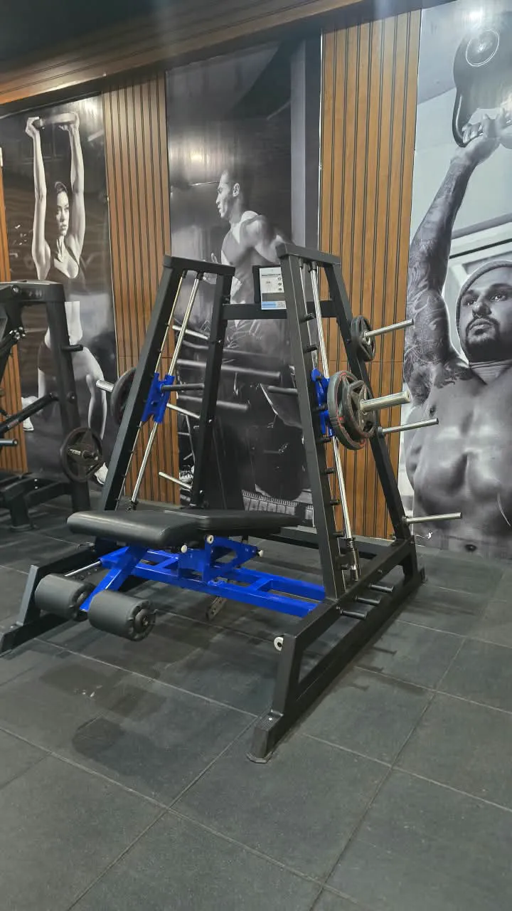 Black and blue Smith machine with an exercise bench in front of gym-wall athlete posters