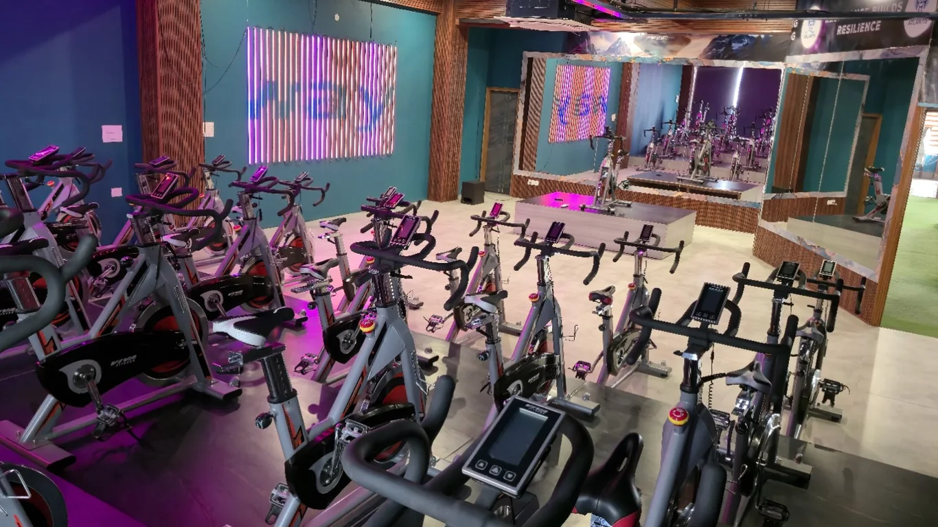 Magenta-lit spin studio with rows of stationary bikes