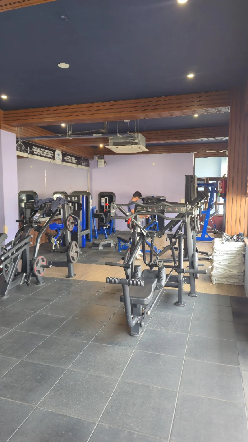 Resistance machines on rubber tiles beside a purple wall