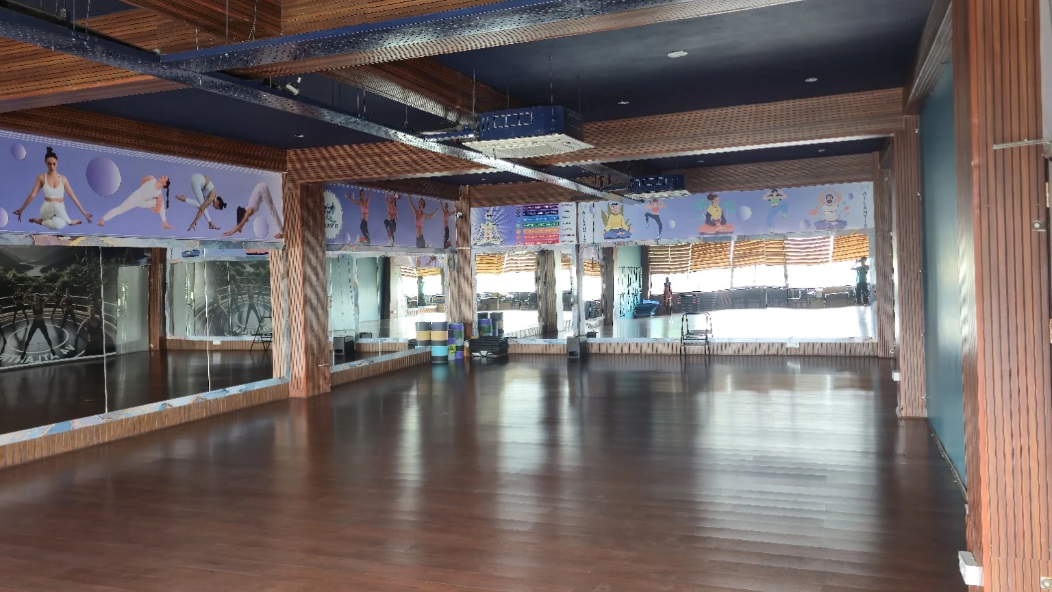 Mirrored yoga and group-class studio with timber flooring, yoga wall graphics and neatly stacked equipment