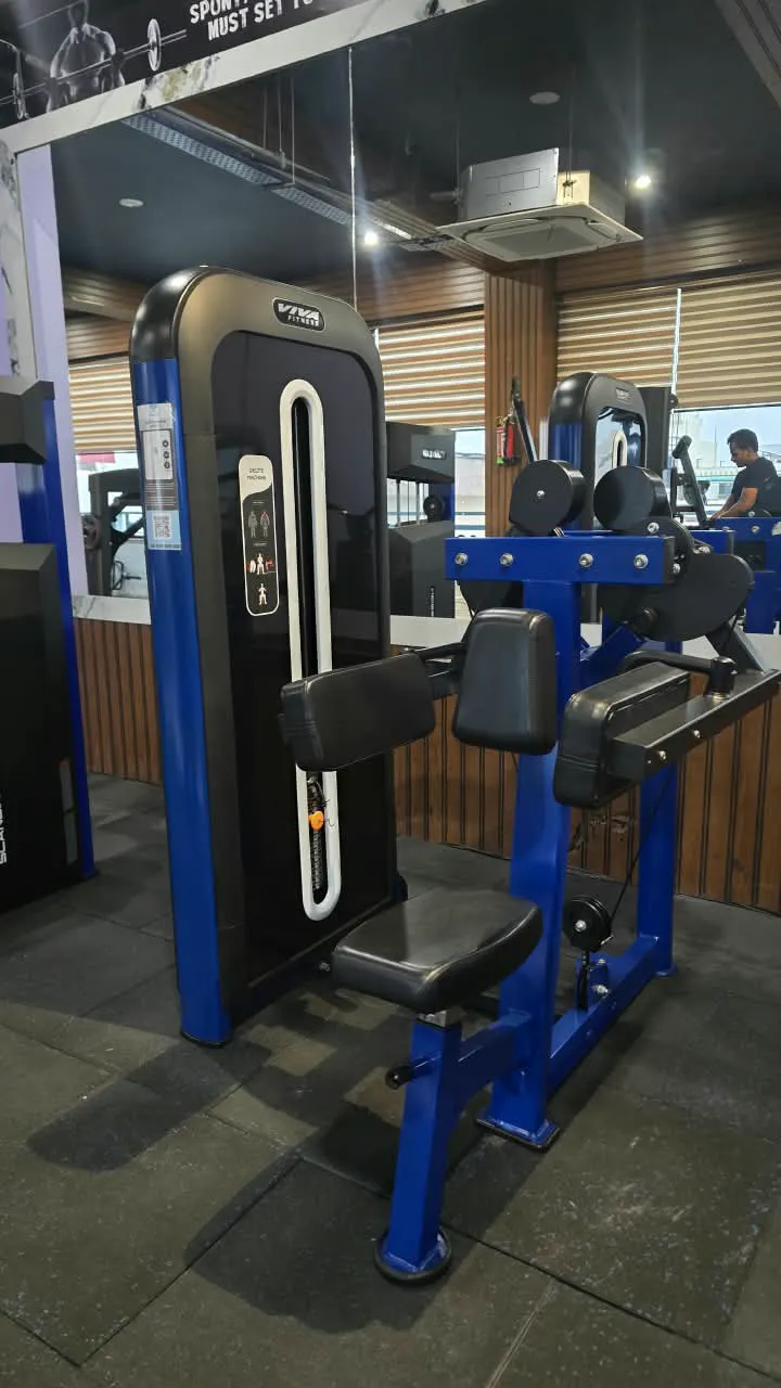 Blue strength machines with padded arm rests on the gym floor